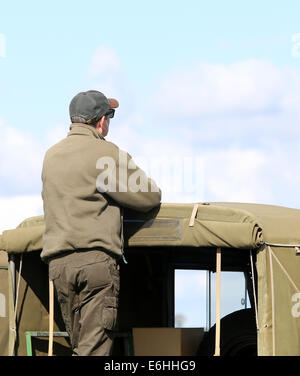 Guy vêtu de l'équipement militaire se tenait sur l'arrière de son camion à regarder, Août 2014 Banque D'Images