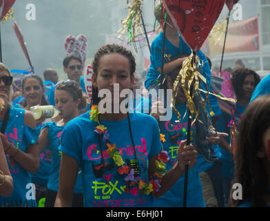 Londres, Royaume-Uni. 24 août, 2014. Une jeune femme dans un tee-shirt bleu, portant une guirlande de fleurs faux porte un cœur en 2014 Notting Hill Carnival journée des enfants Banque D'Images