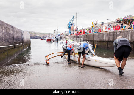 L'équipe d'aviron de six hommes le lancement d'une pirogue à Playa San Juan, Tenerife, Canaries, Espagne. Banque D'Images