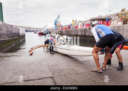 L'équipe d'aviron de six hommes le lancement d'une pirogue à Playa San Juan, Tenerife, Canaries, Espagne. Banque D'Images