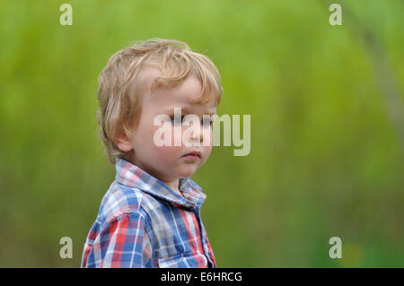 Portrait d'un petit garçon pris en plein air avec un fond vert Banque D'Images