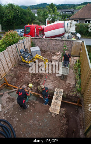 Builders le coulage du béton dans les fondations de l'extension maison à Hay-on-Wye Powys Pays de Galles UK Banque D'Images