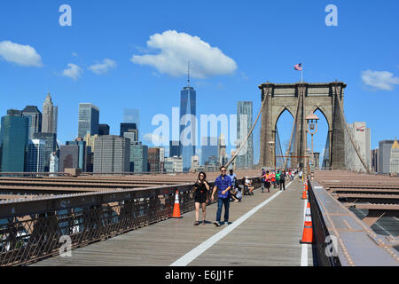 Les personnes qui franchissent le pont de Brooklyn avec le Lower Manhattan skyline en arrière-plan. Banque D'Images