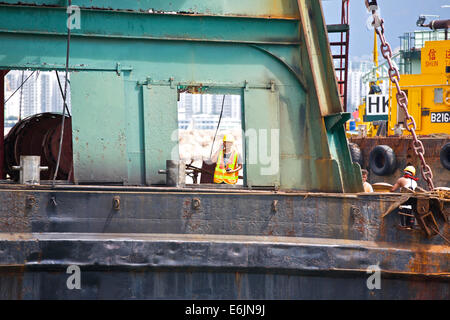 Conversation sur le travail. Des pourparlers sur son mobile ingénieur sur un derrick barge dans le typhon Causeway Bay Hong Kong, un abri. Banque D'Images