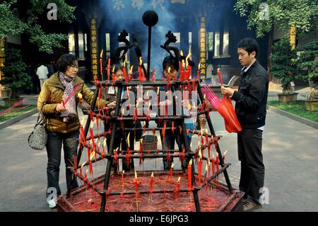 XINDU, CHINE : fidèles visiteurs bouddhiste encens lumière (joss) à partir d'un support en fonte hexagonal en feu avec des bougies Banque D'Images