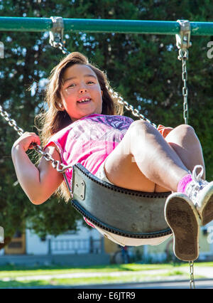 Photographie d'été de sept ans, fille, sur une aire de swing Banque D'Images