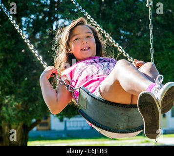 Photographie d'été de sept ans, fille, sur une aire de swing Banque D'Images