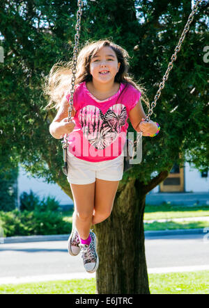 Photographie d'été de sept ans, fille, sur une aire de swing Banque D'Images