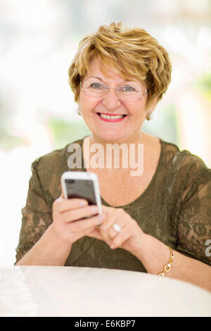 Cheerful senior woman using smart phone at home Banque D'Images