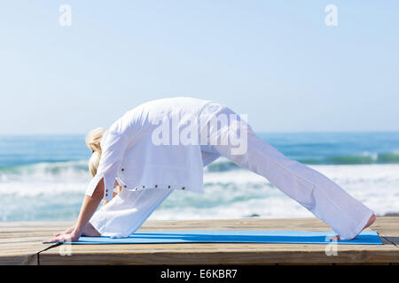 Middle aged woman doing yoga exercice par la plage Banque D'Images