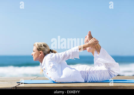 Femme mature en bonne santé faisant du yoga en plein air on beach Banque D'Images