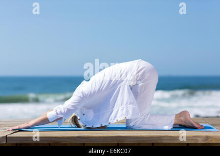 Mature Woman stretching actif à la plage Banque D'Images