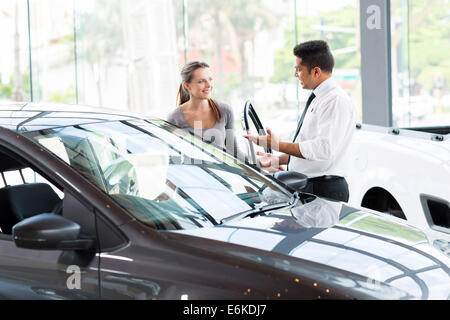 Friendly concessionnaire automobile montrant jeune femme nouvelle voiture Banque D'Images