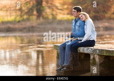 Jeune couple pacifique par l'étang de pêche en automne Banque D'Images