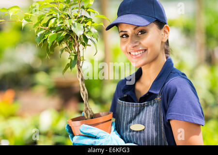 Happy female nursery worker holding potted plant Banque D'Images