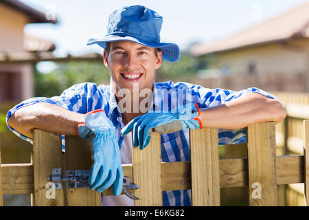 Jeune homme se reposant par jardin clôture après avoir fait quelques travaux dans la cour Banque D'Images