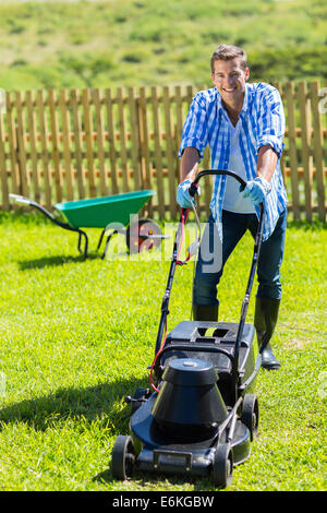 Cheerful man à la tonte du gazon dans son jardin d'accueil Banque D'Images