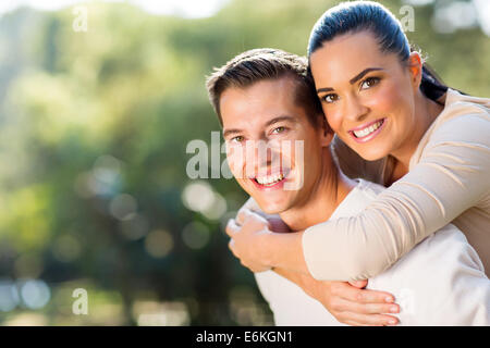 Happy woman piggyback ride on boyfriends back outdoors Banque D'Images