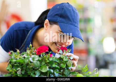 Happy female florist smelling flower in nursery Banque D'Images