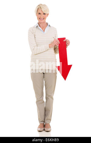 Belle senior woman holding flèche rouge pointant vers le bas sur fond blanc Banque D'Images
