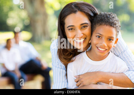 Happy Indian mother hugging son fils en face de famille en plein air Banque D'Images