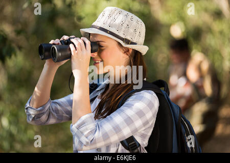 Cheerful young woman using binoculars observation des oiseaux en forêt Banque D'Images