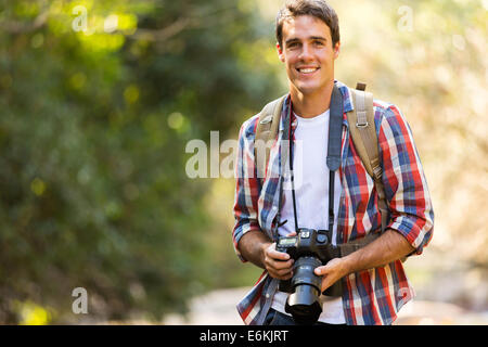 Beau jeune homme de la randonnée dans la vallée de montagne avec votre appareil photo reflex numérique Banque D'Images