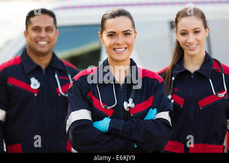 Belle jeune EMT avec des collègues en face de ambulance Banque D'Images