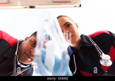 Low angle view of paramedics putting oxygen mask on patient Banque D'Images