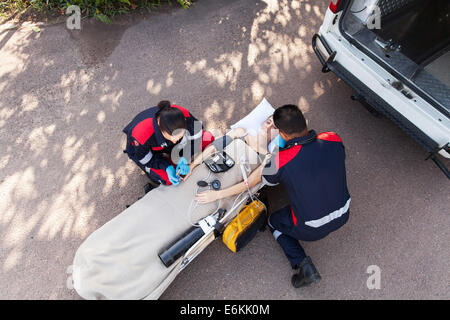 Vue supérieure de l'équipe paramédicale pour prodiguer les premiers soins pour femme inconsciente Banque D'Images