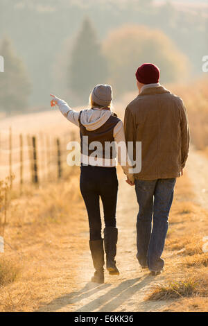 Vue arrière du jeune couple walking in country road Banque D'Images