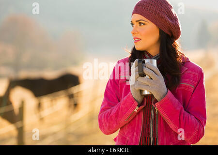 Thoughtful woman in winter clothes holding boisson chaude à l'extérieur Banque D'Images