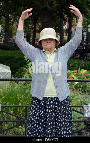 Une vieille femme chinoise Falun Dafa en exercices pratiques Suare Union Park à New York. C'est la position debout de Falun. Banque D'Images