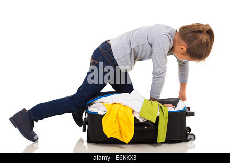 Jeune fille de genou sur suitcase essayant de zip it up Banque D'Images