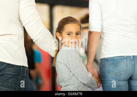 Cute little girl holding hands de son parent et à la recherche Retour à l'aéroport Banque D'Images