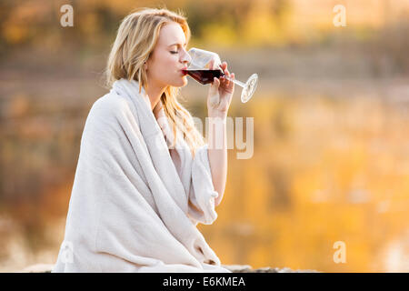 Belle blonde Femme buvant du vin rouge au coucher du soleil Banque D'Images