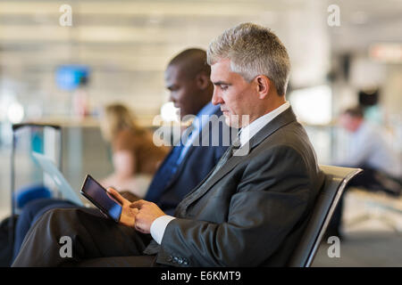 À l'aéroport passagers masculins senior using tablet computer en attendant son vol Banque D'Images