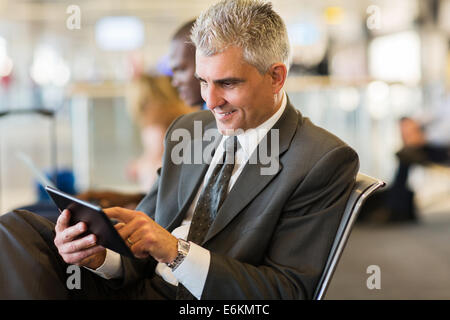 Senior businessman using tablet computer en attendant son voyage a l'aéroport Banque D'Images