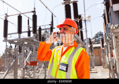 Technicien d'âge moyen talking on cell phone in substation Banque D'Images