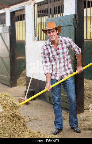 Jeune et beau travail de cow-boy dans stable Banque D'Images