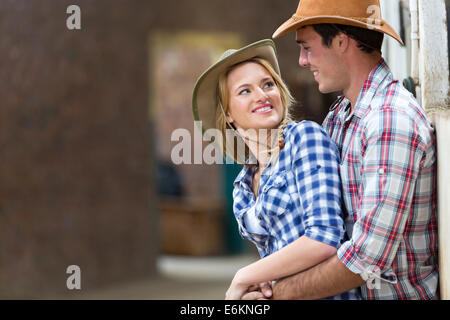 Happy young couple embracing in ferme d'équitation Banque D'Images