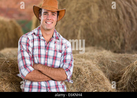 Beau cowboy debout contre des balles de foin Banque D'Images