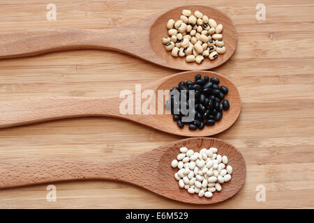 Les haricots dans une cuillère en bois : haricots blancs, haricots noirs et Black Eyed Peas. Banque D'Images
