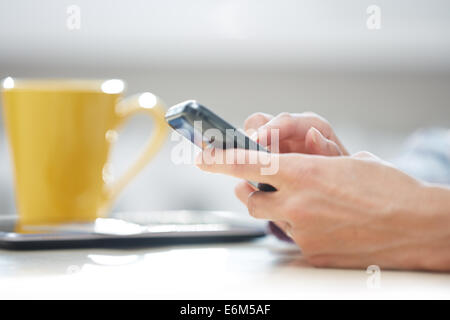 Mains de femme l'envoi de SMS via smartphone au déjeuner Banque D'Images