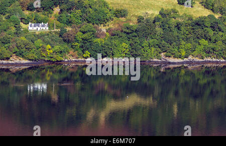 Highland cottage blanc et hillside reflétée dans le Loch Carron près de North Strome Wester Ross Highlands écossais UK Banque D'Images