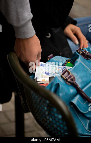 Dresde, Allemagne. 21e Août, 2014. ILLUSTRATION - un homme vole l'argent d'un sac à main de femme à la station de bus et tramway de Dresde, Allemagne, 21 août 2014. Photo : ARNO BURGI/dpa/Alamy Live News Banque D'Images