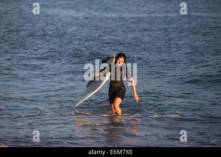 Woman holding surfboard et sortir de l'eau Banque D'Images