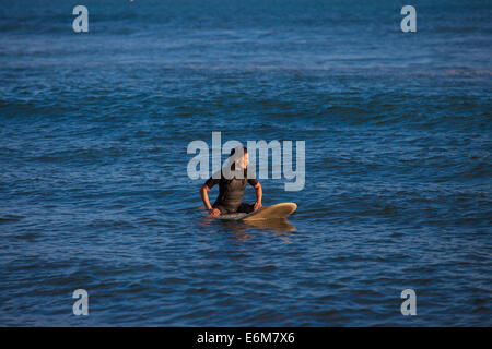 Femme assise sur une planche de surf flottant sur l'eau Banque D'Images