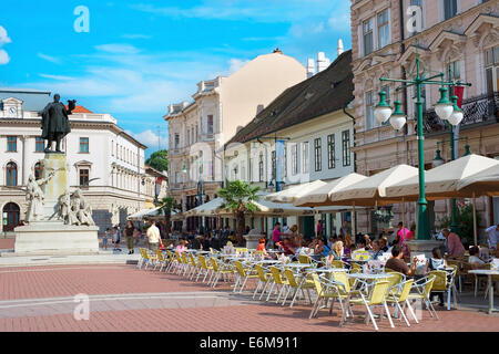 Les gens de la rue à un restaurant de la vieille ville de Szeged. Dans la sculpture Lajos Kossuth à gauche. Banque D'Images