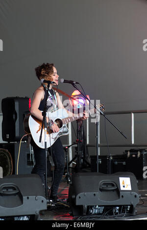 Jeune femme chante et joue de la guitare acoustique sur scène lors de performances à la victorieuse festival 2014 england uk southsea Banque D'Images